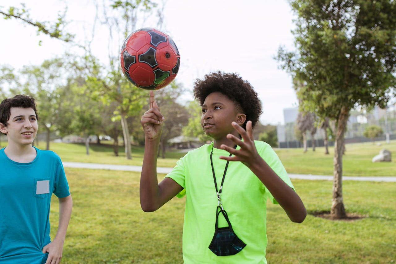 Two teenage boys playing soccer together in a sunny park, enjoying the outdoors.
